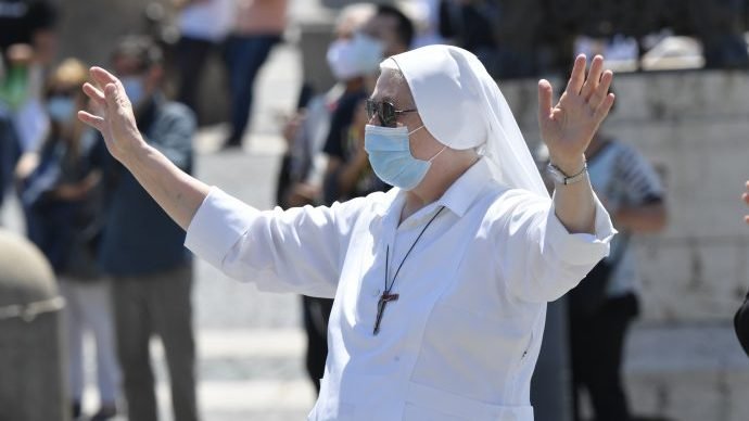 A nun wears a mask as she attends Pope Francis' recitation of the "Regina Coeli" from the window of his studio overlooking St. Peter's Square at the Vatican May 31, 2020, Pentecost Sunday. The pope led the Sunday prayer from his window for the first time in three months after the square was reopened. The pope had been delivering the weekly prayer virtually due to lockdown measures. (CNS photo/Vatican Media via Crux)
