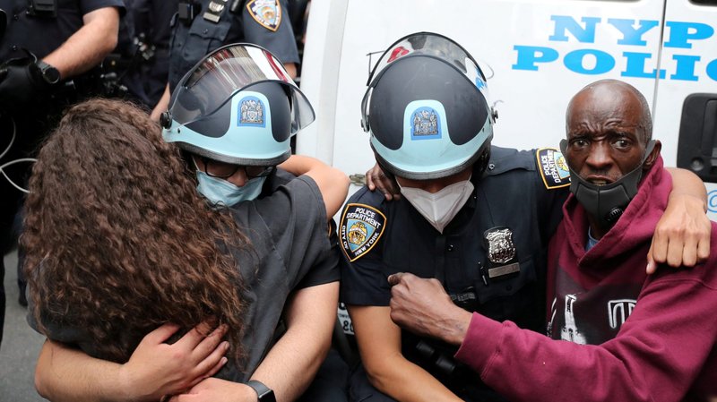 New York City police officers embrace demonstrators during a protest June 2, 2020, following the death of George Floyd, an unarmed African American man whose neck was pinned to the ground by police for more than eight minutes before he was taken to the hospital. (CNS photo/Jeenah Moon, Reuters)