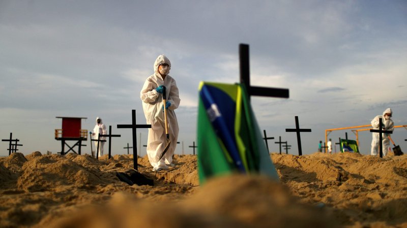 Activists in protective gear dig "graves" on Copacabana beach in Rio de Janeiro June 11, 2020. The graves were dug to symbolize those who died from COVID-19. (CNS photo/Pilar Olivares, Reuters)