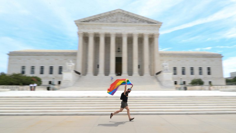 A person runs with a gay pride flag in front of the U.S. Supreme Court building in Washington June 15, 2020. In a 6-3 vote that same day, the Supreme Court said LGBT people are protected from job discrimination by Title VII of the Civil Rights Act of 1964. (CNS photo/Tom Brenner, Reuters)