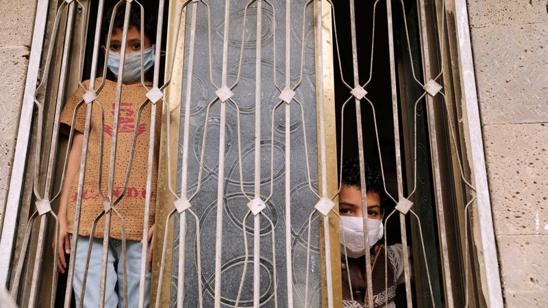 Children wearing protective masks look out the window of their home in Sanaa, Yemen, June 7, 2020, during the COVID-19 pandemic. (CNS photo/Khaled Abdullah, Reuters)