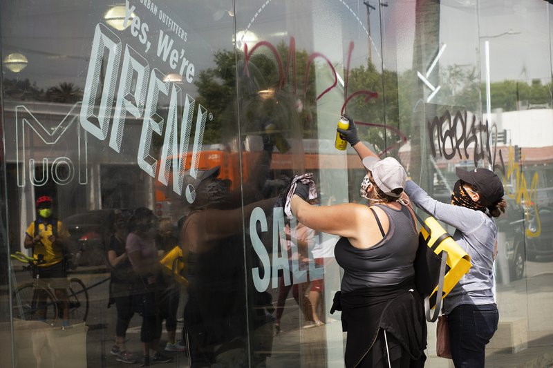 Volunteers clean graffiti and debris from a storefront on Melrose Avenue in Los Angeles on Sunday, May 31, after riots broke out during local protests against the death of George Floyd. (Victor Alemán)
