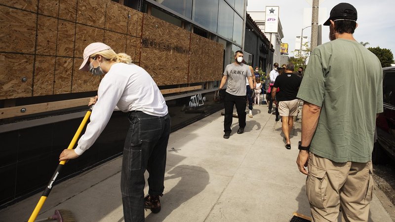 Volunteers clean up on Melrose Avenue in Los Angeles on Sunday, May 31. Several storefronts were vandalized by looters after local protests against the killing of George Floyd became destructive Saturday night. (Victor Alemán)