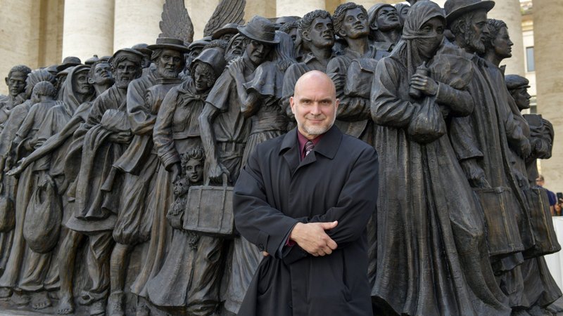 Canadian artist Timothy Schmalz poses in front of his bronze statue depicting a group of migrants and refugees, in St. Peter's Square at the Vatican Sept. 29, 2019. (CNS photo/Paolo Galosi, pool)