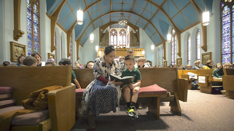 Susana Solorza, a Spanish teacher at Holy Name of Jesus Catholic School in Henderson, Ky., reads along with a student during a school Mass March 28, 2018. (CNS photo/Tyler Orsburn)