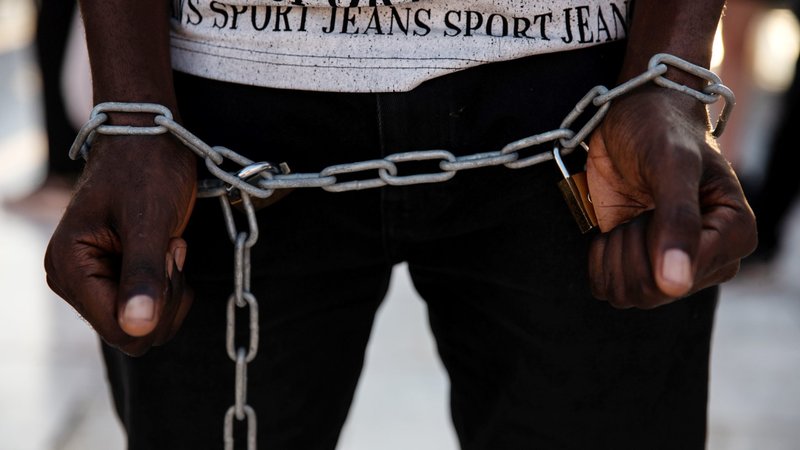 A man in Athens, Greece, has a chain wrapped around his wrists in this photo illustration. (CNS photo/Alkis Konstantinidis, Reuters)