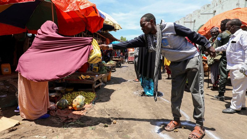 A Somali woman sells fruits to a customer standing at a social distancing marker in late April in Mogadishu, Somalia, during the COVID-19 pandemic. (CNS photo/Feisal Omar, Reuters)