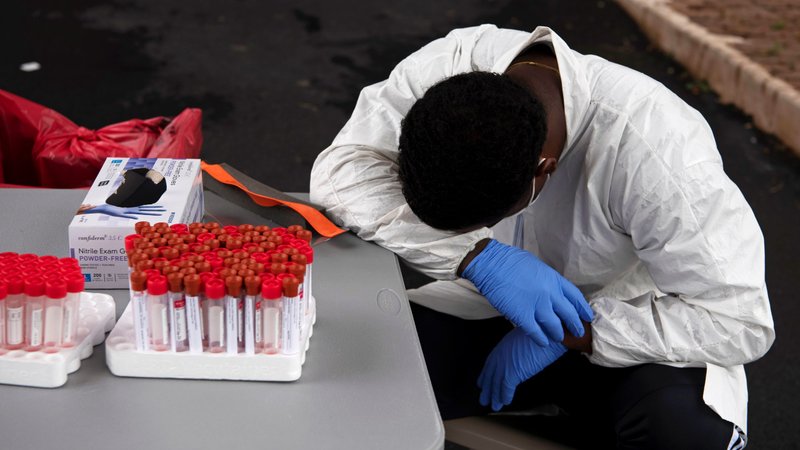 An exhausted health care worker in Houston takes a break July 7, 2020, as people wait in their vehicles to get tested for the coronavirus disease. (CNS photo/Callaghan O'Hare, Reuters)