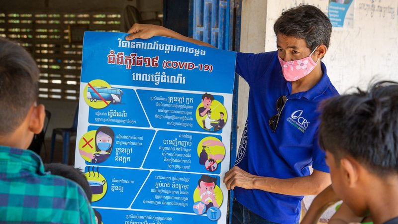 A Catholic Relief Services staff member in Cambodia explains the latest COVID-19 information to a small group of village leaders. (CNS photo/Jennifer Hardy, CRS)