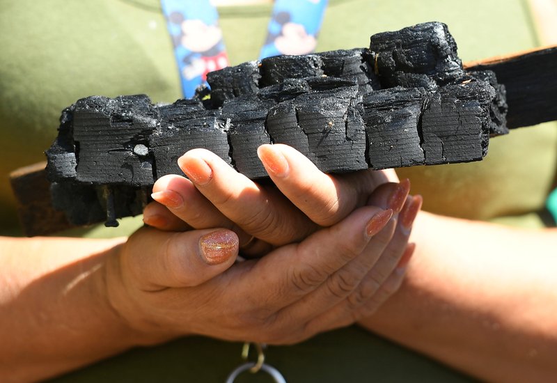A parishioner holds charred wood from the fire-damaged San Gabriel Mission. (Photo by John McCoy)