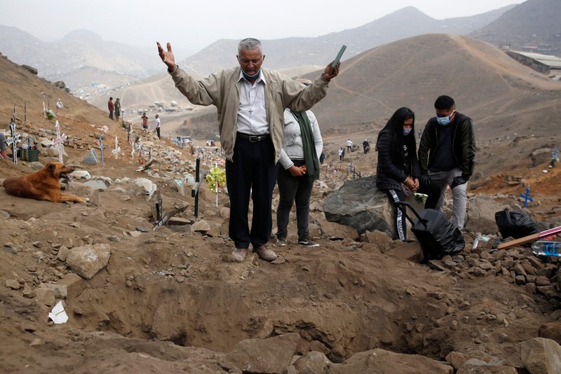 A man holding a Bible prays at a cemetery in Lima, Peru, May 27, during a burial for a person who died from COVID-19. (Catholic News Service/Sebastian Castaneda, Reuters)