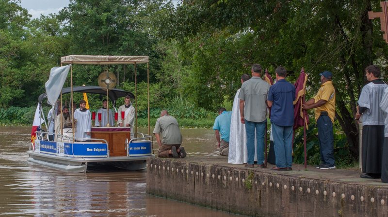 A priest, members of the Knights of Columbus and lay Catholics greet an arriving boat with altar servers in Arnoldville, La., during the Aug. 15, 2017, Fete-Dieu du Teche procession. The Lafayette Diocese will hold its annual 40-mile eucharistic boat procession Aug. 15, 2020, to celebrate the feast of the Assumption, and this year's event will be offered in petition for the end of the coronavirus. (CNS photo/courtesy Chris Lancon)