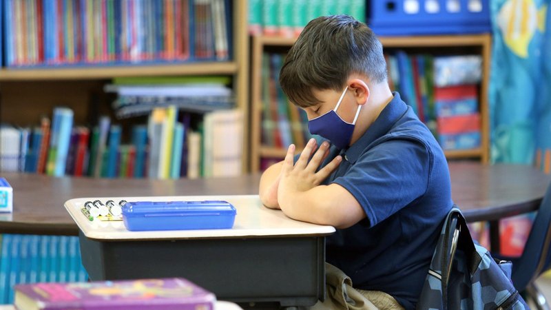 Erik Saldana prays at the beginning of the first day of classes at Holy Cross School in Anderson, Ind., Aug. 5, 2020, with strict COVID-19 policies in place, including mandatory face masks, hand sanitizing and social distancing. (CNS photo/Bob Nichols, Catholic Moment)