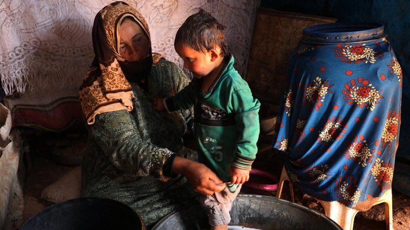 Fawza Umri helps her son put on clothes after being bathed inside their tent at Atmeh camp, near the Turkish border in Syria, June 13, 2020. Humanitarian groups have accused Turkey of "weaponing water" in the northeast region of Syria. (CNS photo/Khalil Ashawi, Reuters)