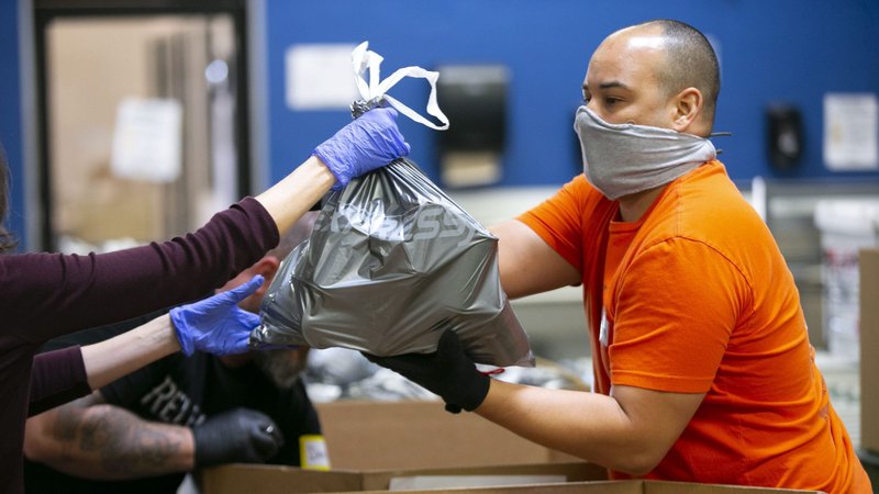 Adam Cadena, a United Food Bank volunteer, takes emergency food bags and places them in boxes at the United Food Bank warehouse in Mesa, Arizona, in this April 16, 2020, file photo. In an interview, Cardinal Pietro Parolin, Vatican secretary of state, said putting a priority on the human person is needed for economic recovery from the coronavirus. (CNS photo/David Wallace, Reuters)