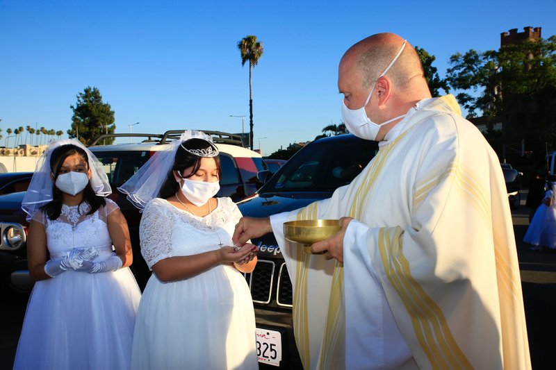 Father David G. Nations, CM, distributes the Eucharist during an outdoor first Communion Mass celebration at St. Vincent de Paul Church in Los Angeles Aug. 1. (Submitted photo)