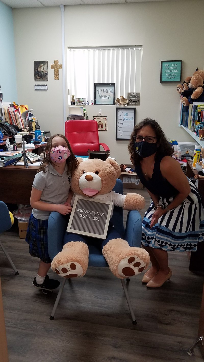 On the first day of school, a second-grader at St. Dorothy School in Glendora stops by to say hello to the principal, Adrienne Ferguson, and visit with Bruno, the school mascot. (JACLYN CHIDESTER)