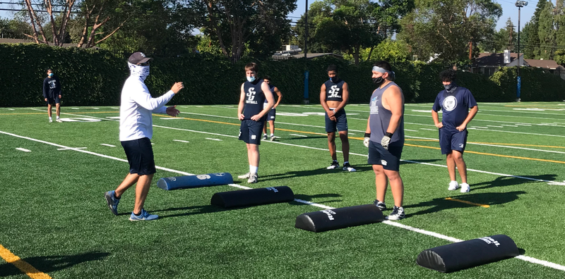 Assistant coach Sean O’Grady (left) leads a “pod” of six St. Genevieve football players in a conditioning drill Aug. 3. (St. Genevieve High School)