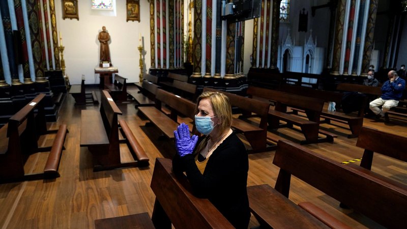 A woman wearing protective gloves and a mask is pictured in a file photo praying in a nearly empty church church in Bilbao, Spain, during the COVID-19 pandemic. (CNS photo/Vincent West, Reuters)