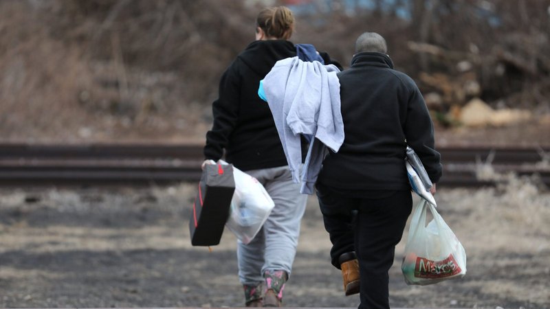 Gina and Jaz, two homeless women from Texas, cross railroad tracks to return to their makeshift shelter in Cleveland Feb. 28, 2018, after receiving a hot meal and clothing from the Knight Riders outreach ministry of St. Paschal Baylon Parish in suburban Highland Heights. (CNS photo/Bob Roller)