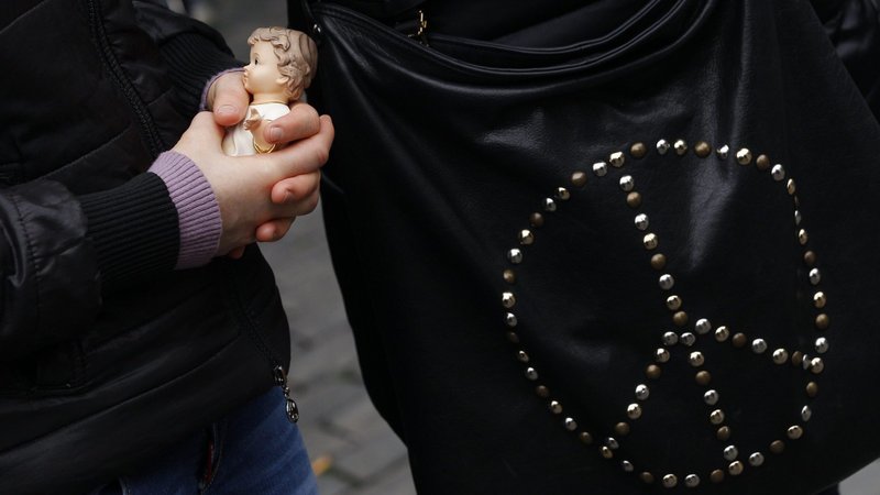 A woman is pictured in a file photo holding a figurine of the baby Jesus next to a purse with the peace symbol in St. Peter's Square at the Vatican. (CNS photo/Paul Haring)