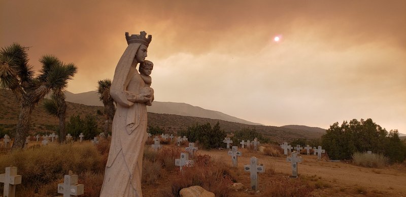 A statue of the Virgin Mary in the cemetery area of St. Andrew’s Abbey in Valyermo stands as the Bobcat Fire burns in the nearby San Gabriel Mountains Sept. 16. (Abbot Damien Toiloro)