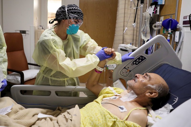 A doctor at Common Spirit's Dignity Health California Hospital Medical Center in Los Angeles takes care of a COVID-19 patient May 18. (Catholic News Service/Lucy Nicholson, Reuters)