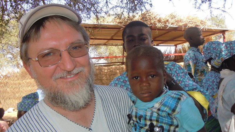 Father Pierluigi Maccalli, a member of the Society of African Missions, is pictured in a file photo with a child in Bomoanga, Niger. Father Maccalli, a 59-year-old native of Crema, Italy, and and three other hostages were released in Mali after being kidnapped more than two years. (CNS photo/Raffaella Russitto, courtesy Society of African Missions)