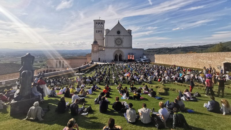 People sit outside the Basilica of St. Francis in Assisi as they attend the beatification Mass of Carlo Acutis in Assisi, Italy, Oct. 10, 2020. The Mass was held inside the basilica but measures to prevent the spread of COVID-19 meant that most of the attendees sat outside. (CNS photo/Junno Arocho Esteves)