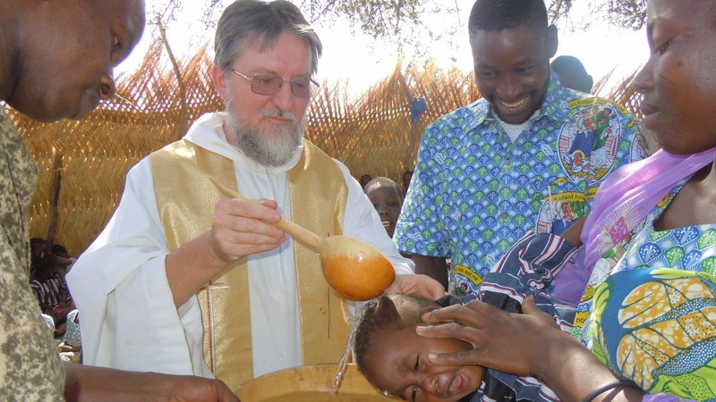 Father Pierluigi Maccalli, a member of the Society of African Missions, is pictured in a file photo baptizing a child in Bomoanga, Niger. Father Maccalli, a 59-year-old native of Crema, Italy, and and three other hostages were released in Mali after being kidnapped more than two years. (CNS photo/Raffaella Russitto, courtesy Society of African Missions)