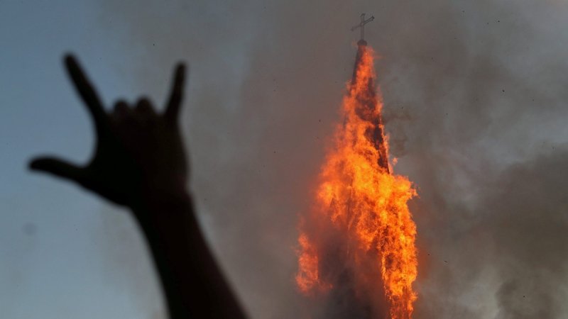 A protester gestures while a church is set on fire during a demonstration against Chile's government in Santiago Oct. 18, 2020, the one-year anniversary of the protests and riots that rocked the capital in 2019. (CNS photo/Ivan Alvarado, Reuters)