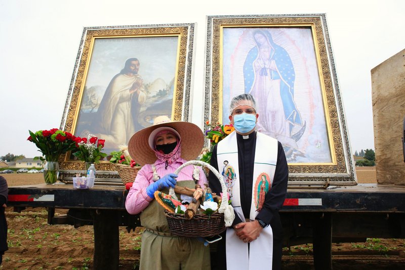 Father Ochoa poses with a farmworker in front of the images. (David Amador Rivera/Angelus News)