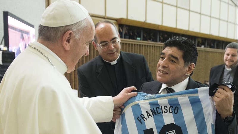Former Argentine soccer star Diego Maradona gives Pope Francis a jersey during a special audience at the Vaticans Paul VI hall in 2014. The pope organized an interreligious "Match for Peace and appealed for an end to conflicts around the world. (CNS photo/L'Osservatore Romano via Reuters)