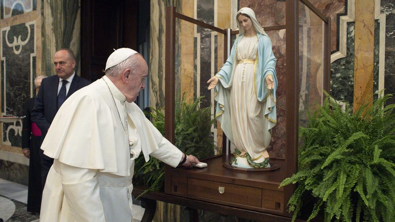 Pope Francis places a rosary in front of a statue of Our Lady of the Miraculous Medal during a private audience at the Vatican Nov. 11, 2020. The statue was about to begin a pilgrimage through Italian dioceses marking the 190th anniversary of Mary's apparition to St. Catherine Laboure. (CNS photo/Vatican Media)