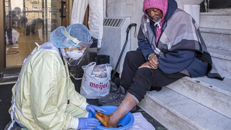 A health care worker, masked for protection from COVID-19, cares for a homeless man at the Pope Francis Center in Detroit in May 2020. The pope is scheduled to mark World Day of the Poor with a Mass and charitable efforts to feed the poor and look after their medical needs. (CNS photo/Jim West)