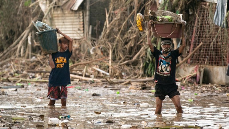 Residents carry their belongings through mud in Manila, Philippines, Nov. 14, 2020, after flooding caused by Typhoon Vamco. Five tropical storms or typhoons have hit the Philippines in a three-week period, including the strongest typhoon since 2013 and the biggest floods since 2009. (CNS photo/Eloisa Lopez, Reuters)