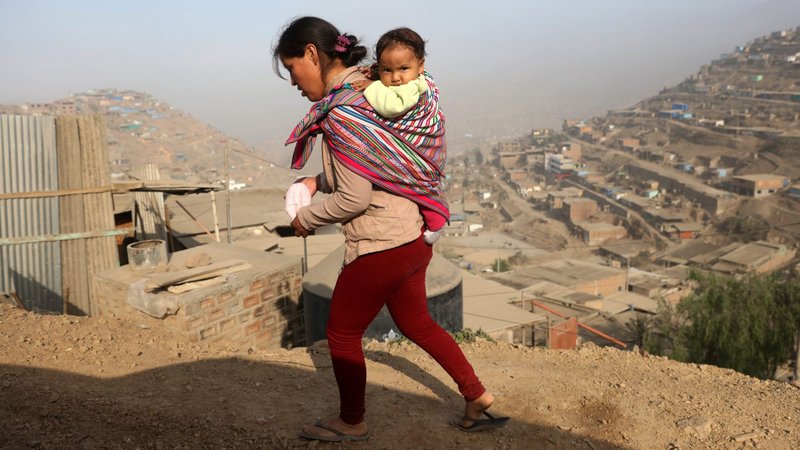 A woman carrying a baby walks on the hills of Villa Maria del Triunfo, on the outskirts of Lima, Peru, in this May 9, 2017, file photo. Cardinal Pedro Barreto of Huancayo, Peru, expressed his hope a new pastoral program of the bishops' conference will not only help Peruvians face the challenges of the coronavirus pandemic but also help them confront the pandemics of corruption, indifference and exclusion plaguing the country. (CNS photo/Guadalupe Pardo, Reuters)