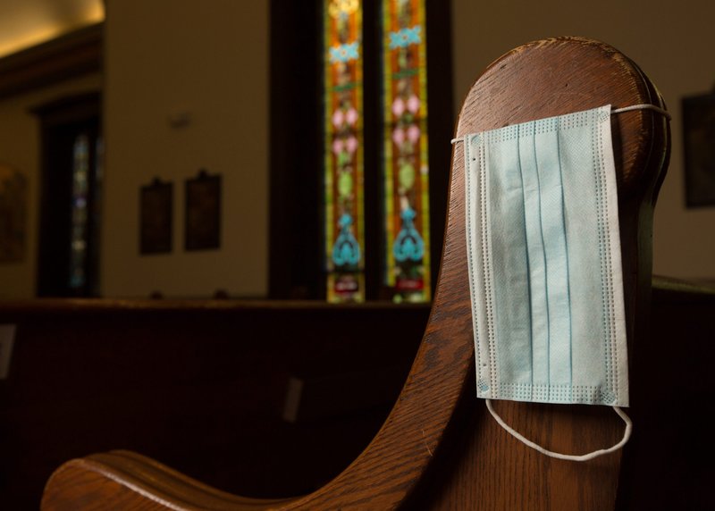 In this illustration photo, a disposable medical mask hangs on the side of a pew at Our Lady of Lourdes Church in Minneapolis, Minnesota. (Catholic News Service/Dave Hrbacek, The Catholic Spirit)