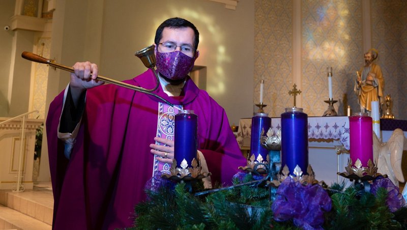 Father Jose Lopez, administrator of SS. Peter and Paul Parish in Green Bay, Wis., lights a candle on the parish's Advent wreath prior to Mass Nov. 28, 2020, the vigil of the first Sunday of Advent Nov. 29. (CNS photo/Sam Lucero, The Compass)