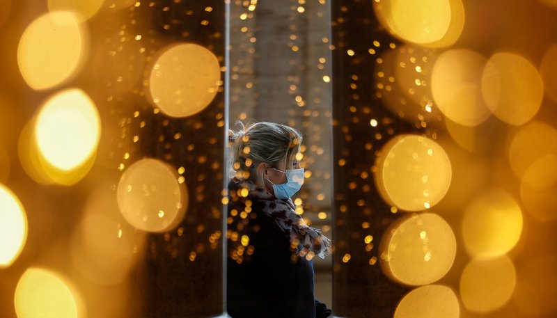 The lights of holiday decorations are seen as a woman wears a mask at a shopping center. (CNS photo/Yara Nardi, Reuters)