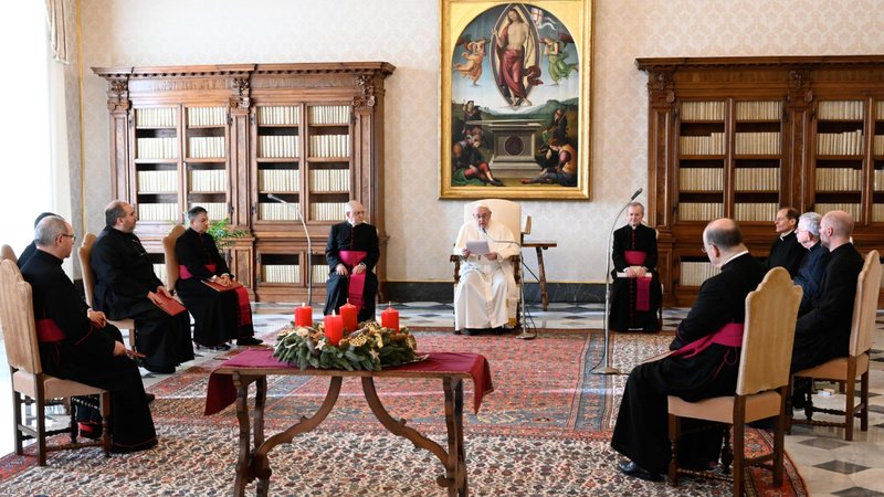 An Advent wreath is seen as Pope Francis leads his general audience in the library of the Apostolic Palace at the Vatican Dec. 9, 2020. The pope continued his series of talks on prayer, reflecting on prayers of petition. (CNS photo/Vatican Media)
