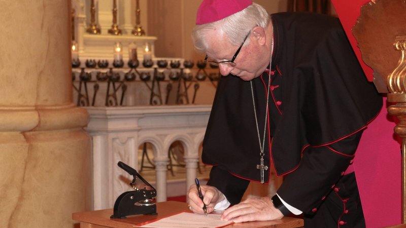 Bishop Francis I. Malone of Shreveport, La., signs a decree of recognition Dec. 8, 2020, at Holy Trinity Catholic Church in downtown Shreveport, officially opening a sainthood cause for five priests who died ministering to people during the yellow fever epidemic of 1873. (CNS photo/Kierstin Richter, courtesy Diocese of Shreveport)