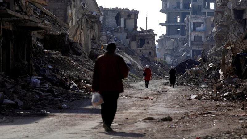 People walk past damaged buildings at the Yarmouk Palestinian refugee camp on the outskirts of Damascus, Syria Dec. 2, 2020. Pope Francis sent a video message Dec. 10 to an online meeting about the Syrian and Iraqi humanitarian crises. (CNS photo/Omar Sanadiki, Reuters)