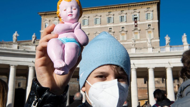 A child holds a figurine of the baby Jesus as Pope Francis leads the Angelus from the window of his studio overlooking St. Peter's Square at the Vatican Dec. 13, 2020. (CNS photo/Vatican Media)