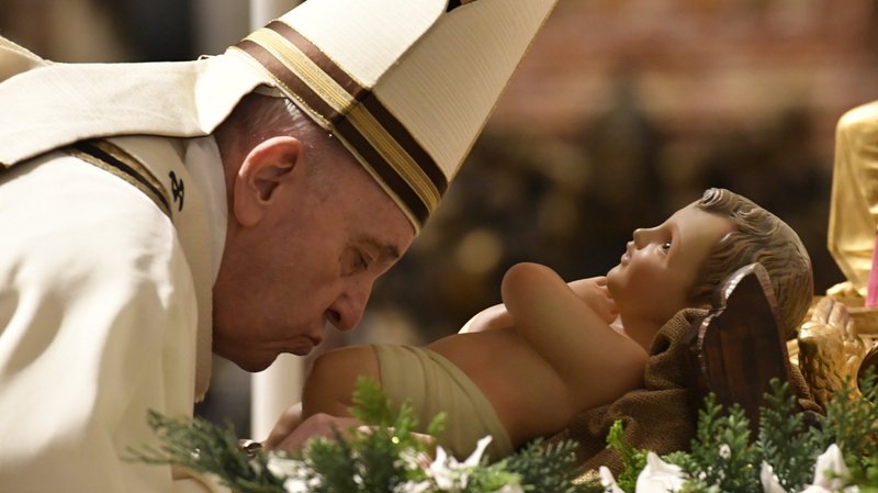 Pope Francis kisses a figurine of the baby Jesus as he celebrates Christmas Eve Mass in St. Peter's Basilica at the Vatican Dec. 24, 2020. The Mass was not open to the general public and began at 7:30 p.m. local time so that the limited number of attendees could return home in time to observe Italy's 10 p.m. curfew. (CNS photo/Vatican Media)