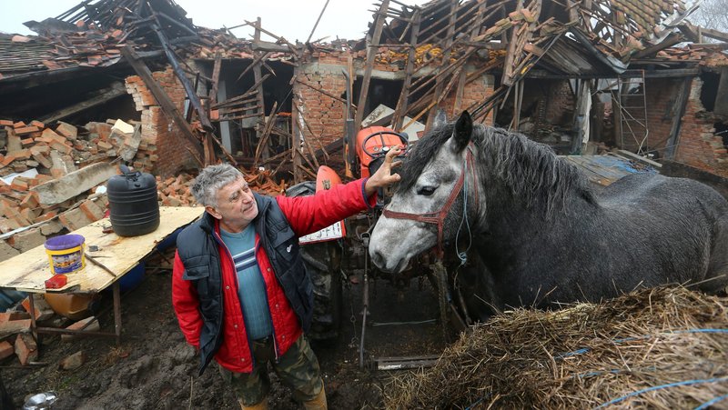 Farmer Tomislav Suknaic touches his horse in front of his destroyed home in the village of Majske Poljane, Croatia, Dec. 30, 2020, following an earthquake. Pope Francis offered condolences and prayers for the victims of the magnitude 6.4 earthquake that rocked central Croatia the previous day, killing at least seven people and injuring dozens. (CNS photo/Antonio Bronic, Reuters)
