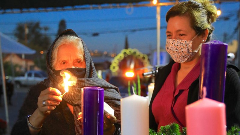 A woman lights an Advent candle before the Saturday vigil Mass outside Our Lady of Solitude Church in East Los Angeles Dec. 5, 2020. (David Amador Rivera)