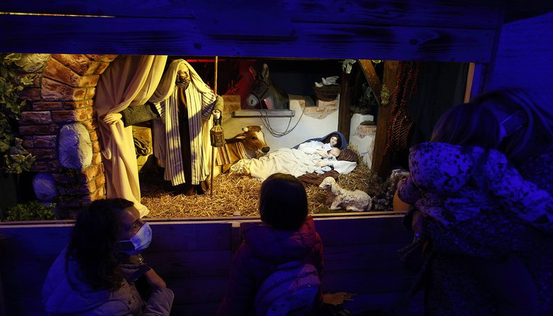 Family members visit the "100 Nativity Scenes at the Vatican" exhibit under the colonnade in St. Peter's Square at the Vatican Dec. 14, 2020. (CNS photo/Paul Haring)