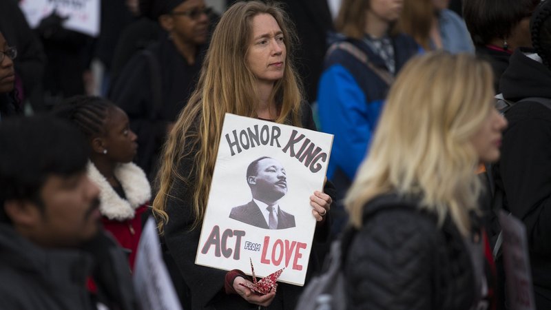 A woman holds a placard with an image of the Rev. Martin Luther King Jr. during a silent prayer walk near his memorial in Washington April 4, 2018. (CNS photo/Tyler Orsburn)