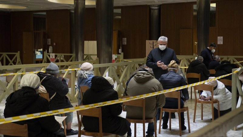 Cardinal Konrad Krajewski, the papal almoner, assists as homeless people receive the first dose of the COVID-19 vaccine in the atrium of the Paul VI hall at the Vatican Jan. 20, 2021. The Vatican said a first group of around 25 homeless people permanently housed in Vatican-owned care and residence facilities received the vaccine. (CNS photo/Vatican Media)